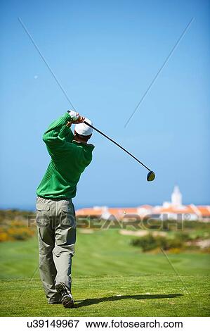 Rear view of golfer holding golf club taking golf swing View Large Photo Image Stock Photo - Rear view of golfer holding golf club taking golf swing. Fotosearch