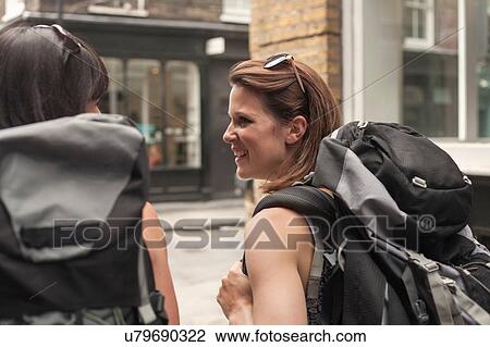 Rear view of two women backpackers strolling along street View Large Photo Image Stock Image - Rear view of two women backpackers strolling along street. Fotosearch