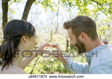 Rear view of young couple making heart shape with hands View Large Photo Image Stock Photography - Rear view of young couple making heart shape with hands. Fotosearch