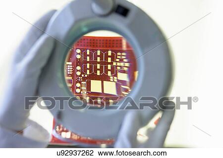 Stock Image - Red circuit board under inspection magnifier in circuit board factory. Fotosearch