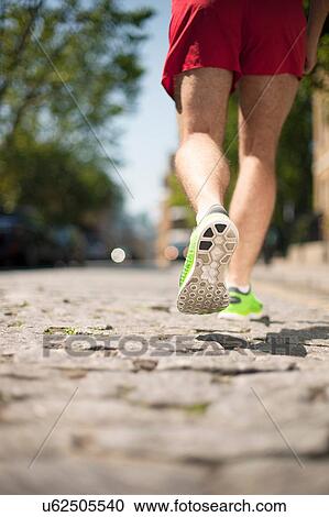 Stock Image - Runner jogging on cobbled street. Fotosearch