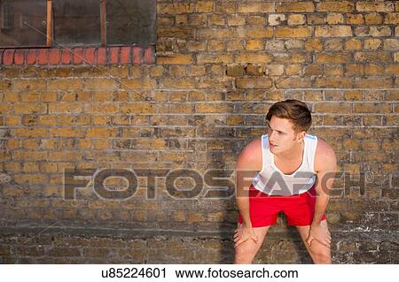 Stock Image - Runner stretching by brick wall. Fotosearch