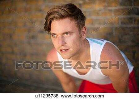 Stock Photo - Runner stretching by brick wall. Fotosearch