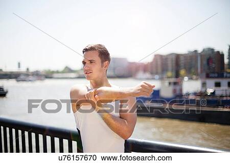Stock Image - Runner stretching on riverfront, Wapping, London. Fotosearch
