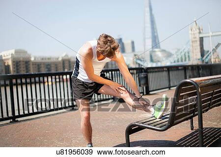 Stock Photo - Runner stretching on riverfront, Wapping, London. Fotosearch