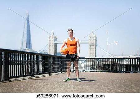 Stock Image - Runner with ball on riverfront, Wapping, London. Fotosearch
