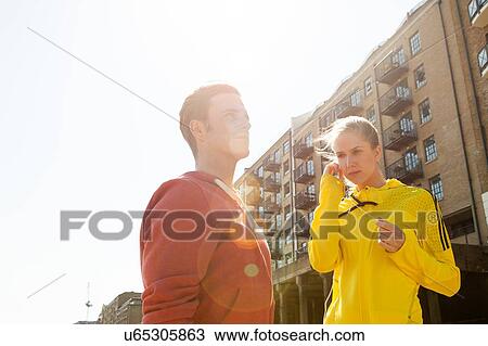 Stock Image - Runners standing by building block, Wapping, London. Fotosearch