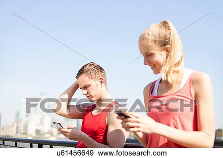 Stock Photo - Runners using smartphone on bridge. Fotosearch