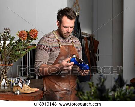 Shoemaker holding blue shoe in workshop View Large Photo Image Stock Photo - Shoemaker holding blue shoe in workshop. Fotosearch