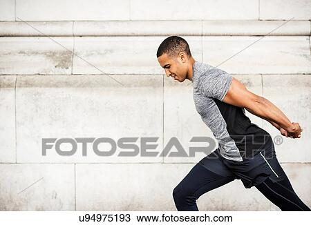 Side view of young male runner warming up with hands behind back View Large Photo Image Stock Image - Side view of young male runner warming up with hands behind back. Fotosearch