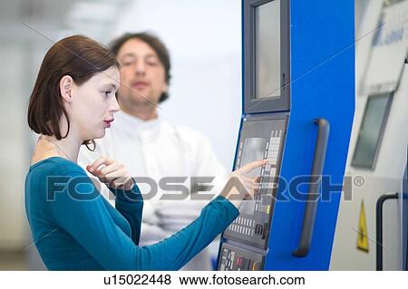 Stock Photo - Side view of young woman pressing keypad on scientific equipment. Fotosearch