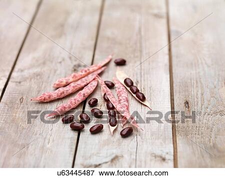 Stock Photo - Still life of red kidney beans and pods on wooden table. Fotosearch