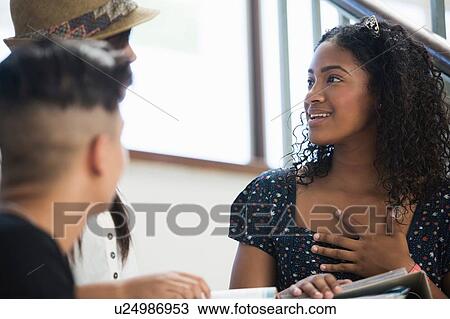 Stock Image - Students on steps, discussing over textbook. Fotosearch