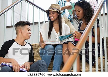 Stock Image - Students on steps, discussing over textbook. Fotosearch