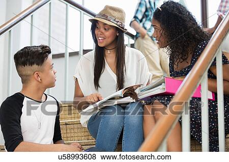 Students on steps, discussing over textbook View Large Photo Image Stock Photo - Students on steps, discussing over textbook. Fotosearch