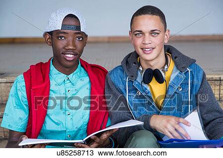 Stock Image - Students on steps, looking up from textbook. Fotosearch