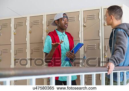 Stock Photography - Students standing beside lockers, chatting. Fotosearch