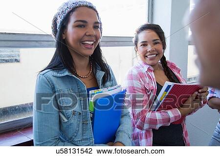 Stock Image - Students standing by window, chatting. Fotosearch
