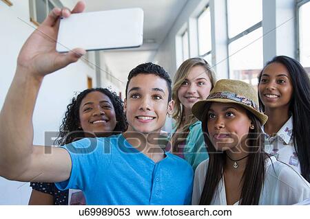 Stock Image - Students standing in hallway, taking selfie. Fotosearch