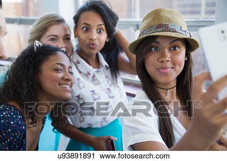Stock Image - Students standing in hallway, taking selfie. Fotosearch