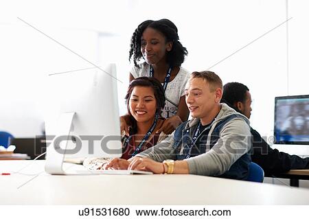 Stock Image - Students typing on desktop computer in classroom. Fotosearch