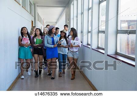 Stock Photography - Students walking down hallway, chatting. Fotosearch