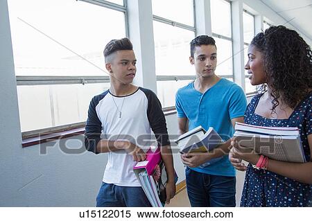 Stock Photography - Students walking down hallway, chatting. Fotosearch