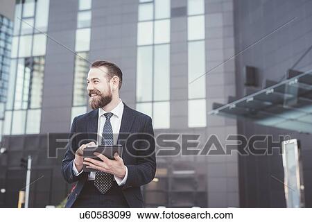 Stylish bearded businessman using digital tablet touchscreen outside office View Large Photo Image Stock Photo - Stylish bearded businessman using digital tablet touchscreen outside office. Fotosearch