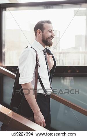 Picture - Stylish businessman carrying jacket moving down city stairway. Fotosearch