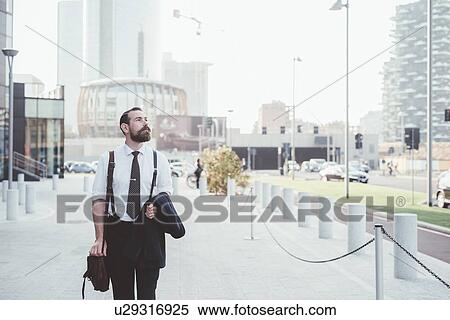 Stylish businessman carrying jacket walking in city View Large Photo Image Stock Photography - Stylish businessman carrying jacket walking in city. Fotosearch
