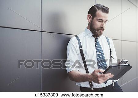 Stylish businessman using digital tablet and smartphone outside office View Large Photo Image Stock Photo - Stylish businessman using digital tablet and smartphone outside office. Fotosearch