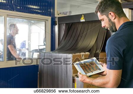 Stock Photograph - Supervisor checking xray using digital tablet in air freight warehouse. Fotosearch