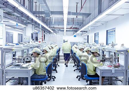 Stock Image - Supervisor overseeing quality check station at factory producing flexible electronic circuit boards. Plant is located in the south of China, in Zhuhai, Guangdong province. Fotosearch