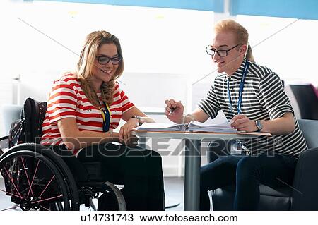 Stock Image - Teacher and female student in wheelchair having classroom tutorial. Fotosearch
