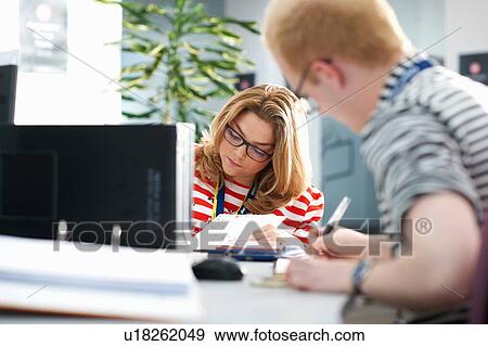 Stock Photo - Teacher and female student writing in classroom tutorial. Fotosearch
