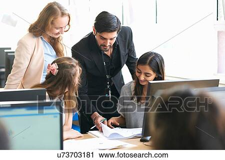 Stock Image - Teacher and group of students working in computer classroom. Fotosearch