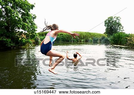Stock Photo - Teenage boy and sister jumping into lake. Fotosearch