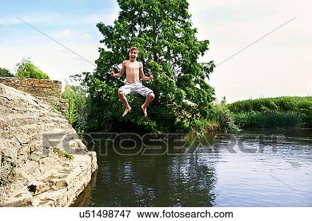 Teenage boy jumping mid air into lake View Large Photo Image Stock Photo - Teenage boy jumping mid air into lake. Fotosearch
