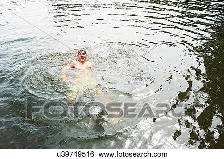 Stock Photograph - Teenage boy swimming in rural lake. Fotosearch
