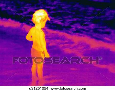 Picture - Thermal image of young boy standing on wet sand, watching tide. Fotosearch