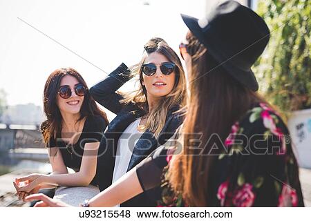 Stock Photo - Three stylish young female friends at city riverside. Fotosearch