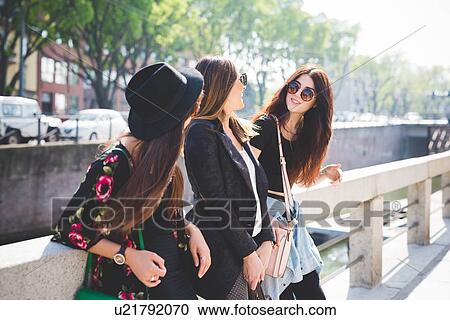 Three young female friends chatting on city riverside View Large Photo Image Stock Image - Three young female friends chatting on city riverside. Fotosearch