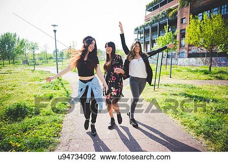 Stock Image - Three young female friends dancing together in park. Fotosearch