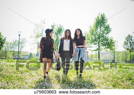 Three young female friends strolling in park View Large Photo Image Stock Image - Three young female friends strolling in park. Fotosearch