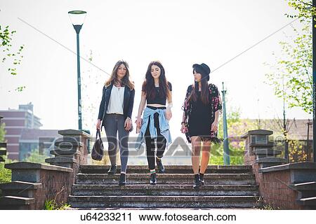 Three young female friends strolling down park stairway View Large Photo Image Stock Image - Three young female friends strolling down park stairway. Fotosearch