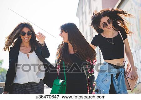 Stock Photo - Three young female friends strolling and fooling around. Fotosearch