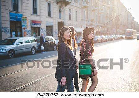 Three young women strolling on city road View Large Photo Image Stock Image - Three young women strolling on city road. Fotosearch