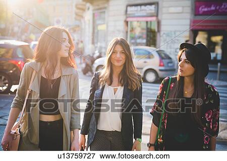 Stock Photo - Three young women strolling on city street. Fotosearch