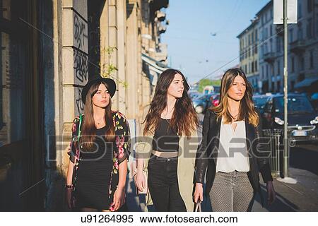 Three young women strolling on city street View Large Photo Image Stock Photography - Three young women strolling on city street. Fotosearch