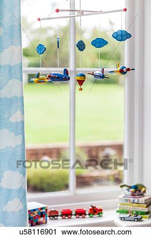 Stock Image - Toy airplane mobile at childs bedroom window. Fotosearch